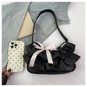 Detail of black satin shoulder bag with layered ruffles and a pink ribbon bow