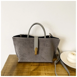 Detailed view of the grey matte tote bag featuring vertical golden metal buckle and leather handle