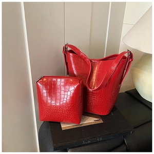 Detailed macro shot of a red crocodile embossed bucket bag set with matching pouch