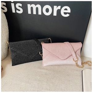 Detail of glittery envelope crossbody bags with rhinestones and gold chain straps