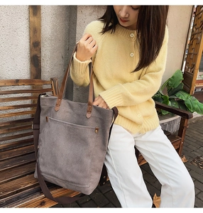 Detail view of large dark grey canvas tote with brown leather handles and sturdy rivets