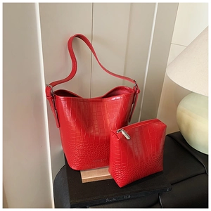 Detailed view of red crocodile embossed leather bucket bag and matching wristlet clutch