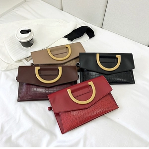 Flat lay of four crocodile-embossed clutch bags with large gold D-ring hardware in various colors