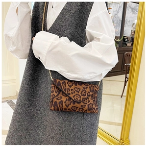 Leopard print envelope bag with gold chain strap shown on model's shoulder