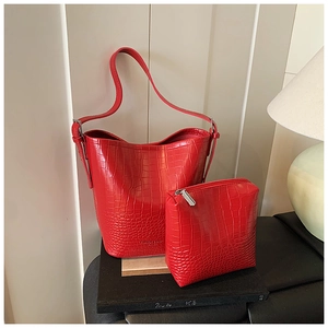 Detail view of red crocodile-patterned bucket bag and pouch with fine embossed texture