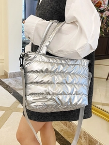 Glossy silver quilted tote bag with puffer texture and adjustable shoulder strap for women