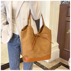 Détail du sac fourre-tout en daim caramel avec nœud en cuir et base renforcée