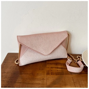 Detail of light pink envelope bag featuring shimmering glitter texture and gold chain strap