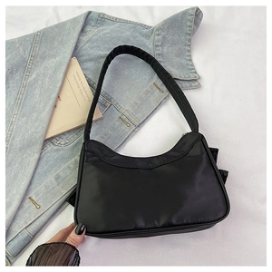 Minimalist black nylon crescent shoulder bag shown in a stylish flat lay aesthetic scene