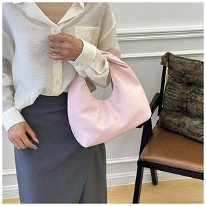 Primer plano de un bolso de hombro de media luna rosa pálido en cuero suave sobre modelo