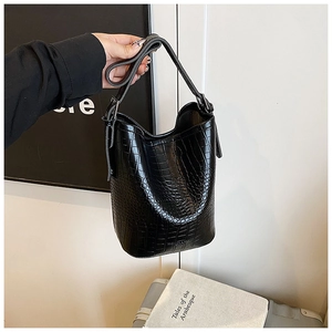 Detail view of the black crocodile pattern texture on a bucket bag with adjustable strap