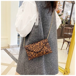 Close-up of leopard print envelope bag with gold chain strap on stylish outfit