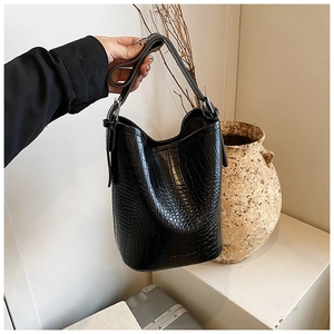 Close-up of black crocodile embossed texture on a bucket bag with silver metal buckles