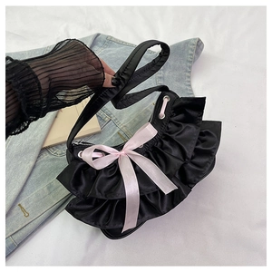 Close-up of black satin underarm bag with pink silk bow and ruffled edges on denim