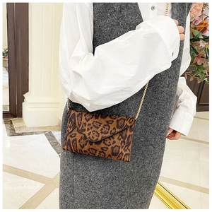 Leopard print envelope bag with gold chain strap shown on model over white shirt