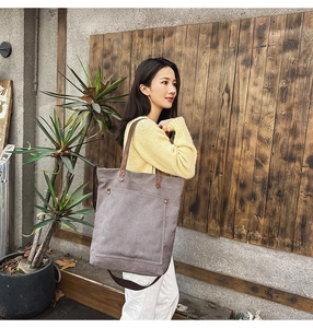 Detail of vintage canvas tote bag with brown leather straps and metal rivets on front pocket