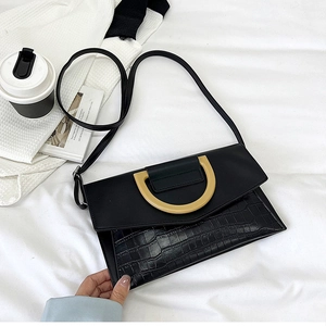 Detail showing the black faux leather texture with crocodile pattern and gold D-ring buckle