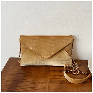 Macro detail of champagne gold glitter envelope clutch bag with golden chain strap