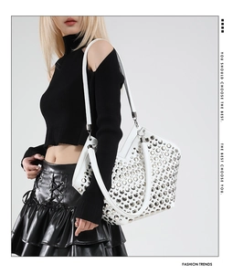 Détail du sac cabas blanc avec clous argentés porté par un mannequin en noir