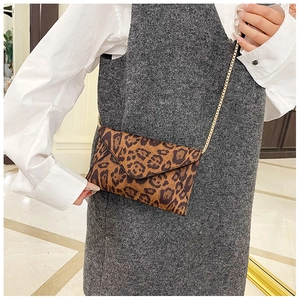 Chic leopard print envelope clutch bag with gold chain strap shown on a model
