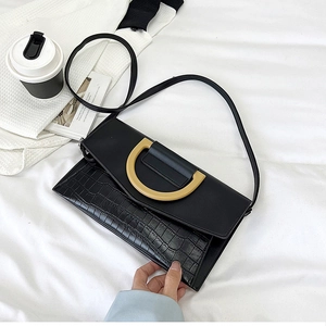 Close-up of black crocodile texture bag featuring a golden D-buckle on white bedding