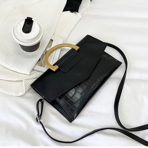 Detailed view of black crocodile pattern leather handbag with light brown D-shaped handle