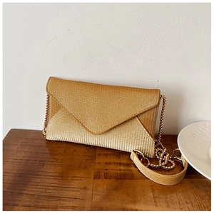Detail shot of the golden envelope evening bag with fine textured glitter and metal chain