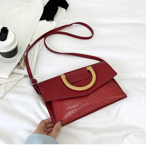 Detail of dark red crocodile pattern handbag with D-shaped gold metal ring buckle