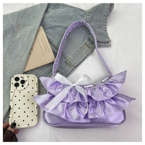 Detail of lavender satin shoulder bag featuring soft ruffles and a white silk bow