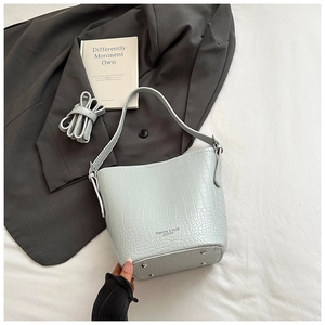Close-up of light blue crocodile texture bucket bag with adjustable shoulder strap detail