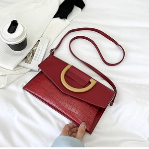 Detail shot of a red crocodile-embossed envelope clutch with a golden metal buckle