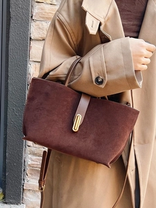 Retro large-capacity brown suede tote bag with metal buckle shown on shoulder of a model