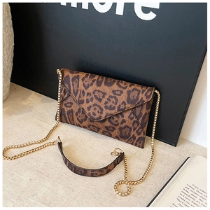 Detail shot of leopard print envelope bag with gold chain strap on artistic background