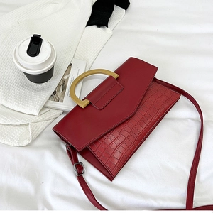 Detail of red crocodile embossed leather handbag with yellow circular handle and strap