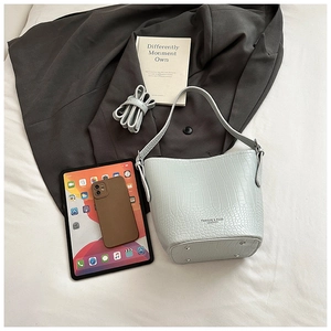 Flat lay of crocodile pattern bucket bag with adjustable strap and interior logo detail