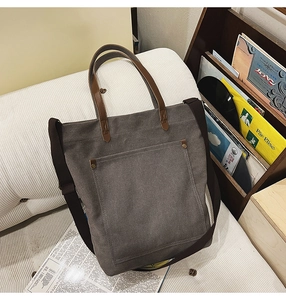 Close-up of vintage dark gray canvas tote bag with brown leather straps and metal rivets