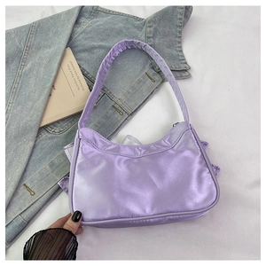Close-up of a purple satin crescent shoulder bag with ruffle edge on a white background