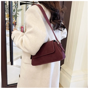 Detail view of burgundy matte underarm bag with gold metal buckle on white coat
