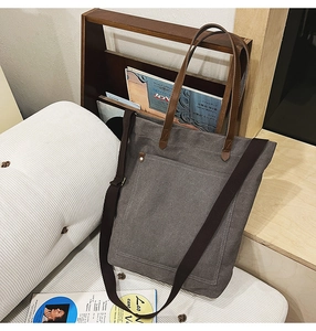 Detail of dark grey canvas tote bag with leather straps on a cozy wooden lifestyle setting