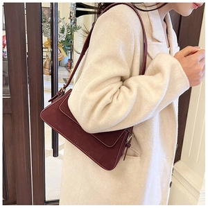 Detail shot of the frosted texture and vintage metal buckle on the burgundy shoulder bag