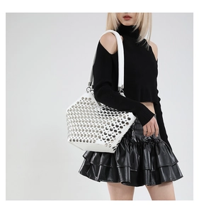 Détails des rivets argentés et texture cuir blanc sur un sac cabas de style punk