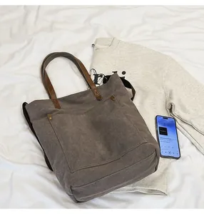 Close-up of vintage canvas tote bag with brown leather handles and sturdy metal rivets