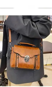 Brown leather crossbody bag with vintage swivel lock and metallic zipper detailing