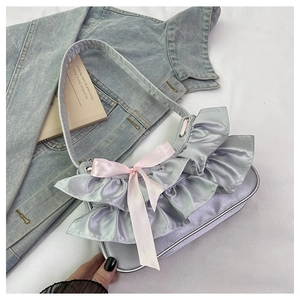 Detail of silver satin hobo bag featuring layered ruffles and a delicate pink bow