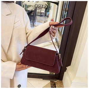 Close-up of matte wine red shoulder bag with golden metallic hardware details