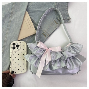 Detail of satin shoulder bag featuring mesh ruffles and a pink ribbon bow accent