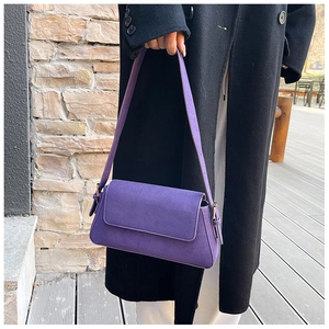 Detail shot of purple suede-textured underarm bag with adjustable strap and metal hardware