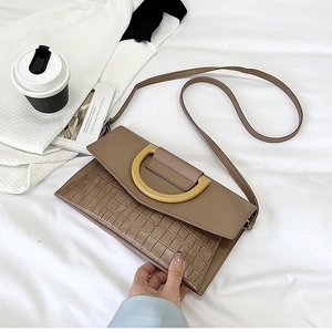 Detail of mocha brown crocodile texture leather bag with yellow metal buckle
