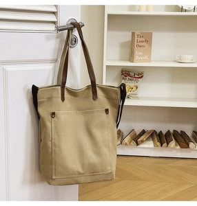 Detailed macro view of khaki canvas tote with brown leather handles and metal rivet accents