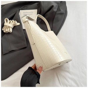 Detailed macro view of cream crocodile texture shoulder bag with silver base studs